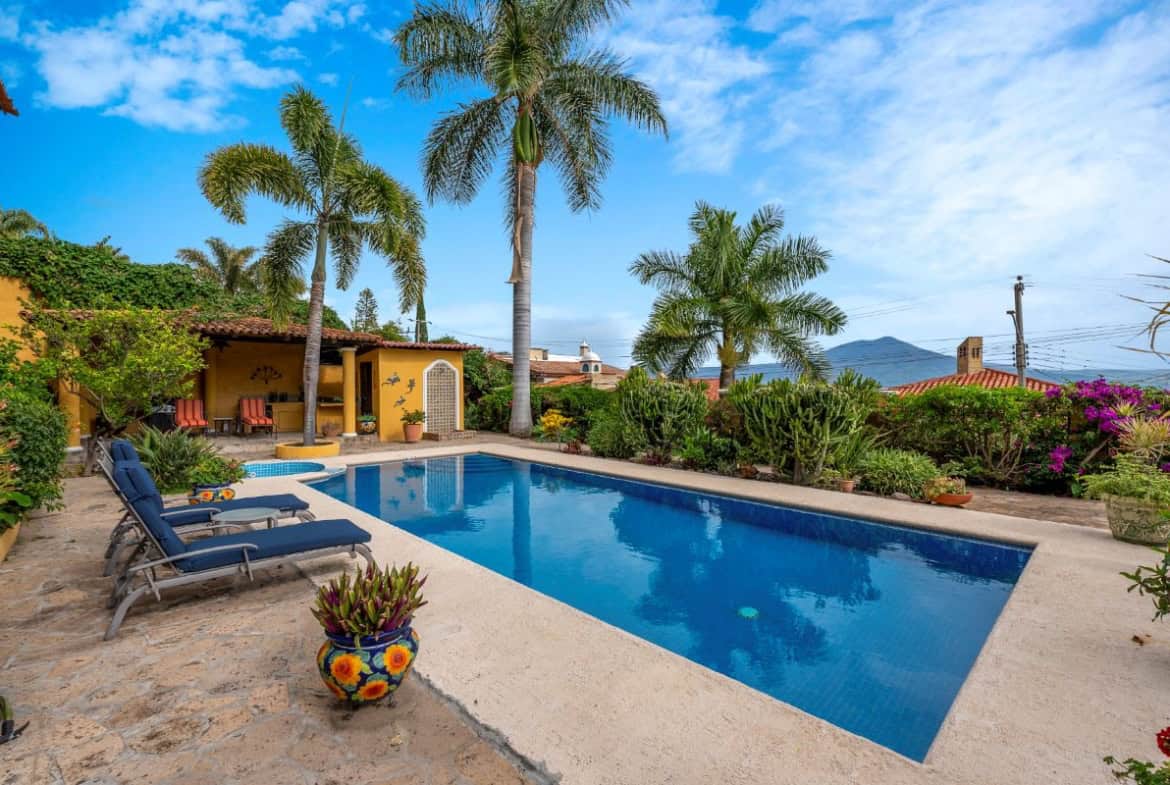 a pool with palm trees and a house