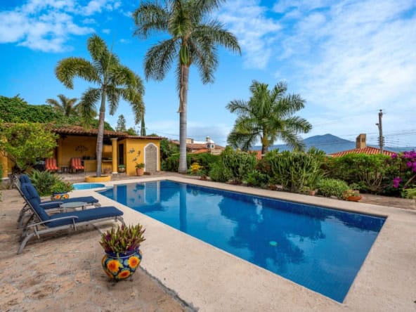 a pool with palm trees and a house